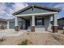 One-story home with gray siding, covered porch, and two-car garage at 40060 W Bravo Dr, Maricopa, AZ 85138