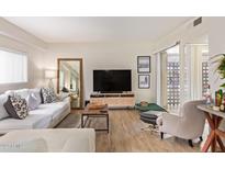 Living room with light colored sofa, armchair, and wood-look flooring at 351 E Thomas Rd # D108, Phoenix, AZ 85012