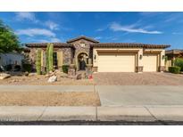 Tan stucco house with stone accents, three-car garage, and desert landscaping at 31811 N 16Th Ave, Phoenix, AZ 85085