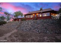 Rustic log cabin home at dusk, nestled on a rocky hillside at 1310 Kenrick Dr, Wickenburg, AZ 85390