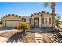 Tan one-story house with red shutters and a nicely landscaped yard at 42609 W Milky Way, Maricopa, AZ 85138