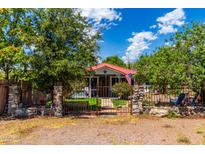 Cute cottage with red metal roof, stone fence, and mature landscaping at 738 W Main St, Superior, AZ 85173