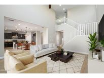 Open concept living room with high ceilings, staircase, and view into kitchen at 1860 W Buckhorn Trl, Phoenix, AZ 85085