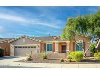 Tan house with a three-car garage, landscaping, and a blue sky at 42531 W Heavenly Pl, Maricopa, AZ 85138
