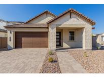 Modern house with light-colored stone facade and brown garage door at 21354 E Sparrow Dr, Queen Creek, AZ 85142