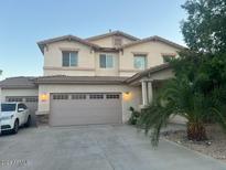 Two-story house with a large garage and a palm tree in the front yard at 18527 W Caribbean Ln, Surprise, AZ 85388
