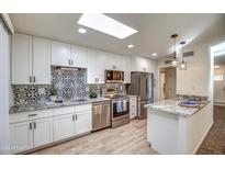Remodeled kitchen with granite countertops, white cabinets, and tile backsplash at 19202 N Signal Butte Cir, Sun City, AZ 85373