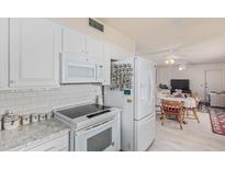 Clean kitchen, white appliances and view into dining area at 9934 W Oak Ridge Dr, Sun City, AZ 85351