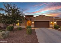 Tan stucco home with two car garage and desert landscaping at 41692 W Monsoon Ln, Maricopa, AZ 85138