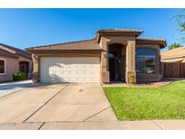 Tan one-story house with a two car garage and manicured lawn at 8752 E Plata Ave, Mesa, AZ 85212