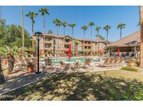 Relaxing pool area with lounge chairs and palm trees at 14950 W Mountain View Blvd # 1208, Surprise, AZ 85374