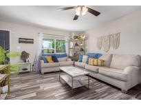 Living room featuring comfortable sofas, a coffee table, and wood-look floors at 3608 W Glenn Dr, Phoenix, AZ 85051