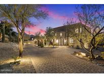 Stunning curb appeal with a brick driveway and beautiful landscaping at dusk at 10793 E La Junta Rd, Scottsdale, AZ 85255