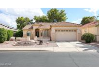 Tan stucco house with tile roof, two-car garage, and landscaped front yard at 17865 W Spencer Dr, Surprise, AZ 85374