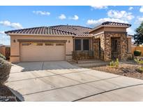 Single-story home with tan colored exterior, tile roof, and a two-car garage at 18195 W Redwood Ln, Goodyear, AZ 85338