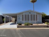 Single-wide mobile home with covered carport and landscaped yard at 5735 E Mcdowell Rd # 162, Mesa, AZ 85215