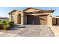 Tan house with brown garage door and landscaping at 15698 W Morning Glory St, Goodyear, AZ 85338