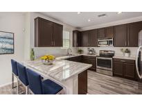 Modern kitchen with dark cabinets, marble countertops, and stainless steel appliances at 7772 W Pipestone Pl, Phoenix, AZ 85035