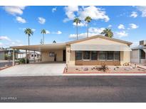 Single-wide manufactured home with covered carport and desert landscaping at 9302 E Broadway Rd # 42, Mesa, AZ 85208