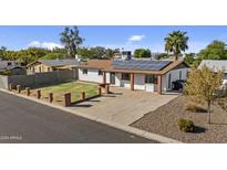 Single story home with solar panels and a well-maintained front yard at 7428 E Carol Cir, Mesa, AZ 85208