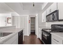 Kitchen with white cabinets, black appliances, and wood floors at 1920 W Lindner Ave # 137, Mesa, AZ 85202
