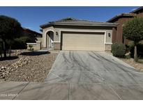 Tan one-story house with a two-car garage and gravel driveway at 20216 W Desert Bloom St, Buckeye, AZ 85326