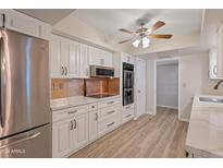 Modern kitchen with white cabinets, stainless steel appliances, and quartz countertops at 13403 N Cedar Dr, Sun City, AZ 85351