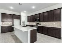 Modern kitchen with dark cabinets, white island, and stainless steel appliances at 7366 E White Tail Rd, San Tan Valley, AZ 85143