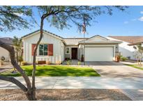 Single-story home with a landscaped lawn, two-car garage, and red shutters at 20428 W Elm Dr, Buckeye, AZ 85396