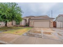 Tan one-story house with a tile roof, two-car garage, and a tree in front at 7951 E Posada Ave, Mesa, AZ 85212