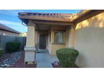 Tan stucco home with covered entryway, mature shrubs, and a walkway leading to the front door at 3347 W Steinbeck Dr, Anthem, AZ 85086