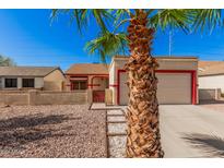House exterior with a beige stucco finish, red accents, and a two-car garage at 10014 N 66Th Ln, Glendale, AZ 85302