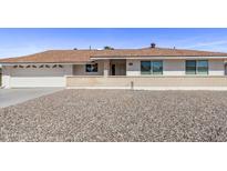 Ranch-style home with a two-car garage and gravel landscaping at 10448 W Caron Dr, Sun City, AZ 85351