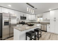 Modern kitchen with white cabinets, granite island, and stainless steel appliances at 6010 W Lewis Ave, Phoenix, AZ 85035