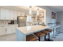 Modern kitchen with white cabinets, stainless steel appliances, and breakfast bar at 8301 E Crestwood Way, Scottsdale, AZ 85250