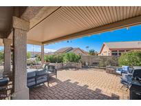 Spacious covered patio with brick pavers, comfortable seating, and a built-in grill at 21610 N 160Th Ln, Sun City West, AZ 85375