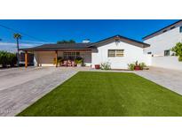White single story home with artificial turf lawn and a wood fence at 4002 E Clarendon Ave, Phoenix, AZ 85018