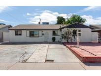 White brick ranch house with a spacious front yard and red brick driveway at 8151 W Clarendon Ave, Phoenix, AZ 85033
