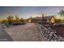 Front view of a ranch-style home with a curved driveway and desert landscaping at 36444 N Stardust Ln, Carefree, AZ 85377