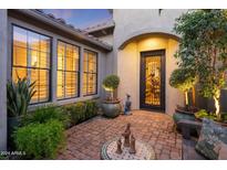 Charming courtyard entry with brick flooring, lush greenery, and ornate door at 4065 N Silver Ridge Cir, Mesa, AZ 85207