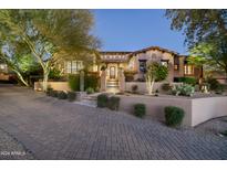 Luxury home exterior at dusk with a brick driveway at 19481 N 98Th Pl, Scottsdale, AZ 85255