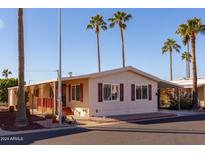 Tan single-wide manufactured home with covered porch and palm trees in the background at 9302 E Broadway Rd # 9, Mesa, AZ 85208