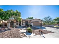 Tan house exterior with a two-car garage and landscaping at 7585 W Tumblewood Dr, Peoria, AZ 85382