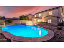 Inviting kidney-shaped pool with surrounding patio and landscape lighting at 2660 S 172Nd Dr, Goodyear, AZ 85338