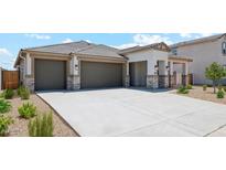 Modern three-car garage home with stone accents and landscaping at 9911 S Caballo Dr, Apache Junction, AZ 85120