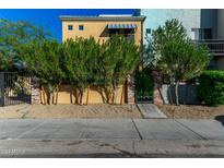 Front view of a two-story home with brick accents, lush landscaping, and gated entry at 1406 W Main St # 137, Mesa, AZ 85201