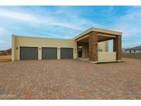 Modern three-car garage home with stone accents and a large driveway at 14930 W El Cortez Pl, Surprise, AZ 85387