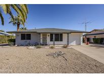 Ranch-style home with gray brick exterior, white trim, and a two-car garage at 18621 N 104Th Dr, Sun City, AZ 85373