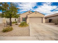 Tan house with a two-car garage and well-manicured landscaping at 18545 N Wilson St, Maricopa, AZ 85138