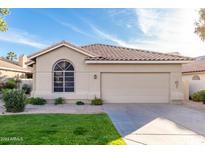 Tan house with a brown tile roof, two car garage, and nicely landscaped lawn at 6653 E Sugarloaf St, Mesa, AZ 85215